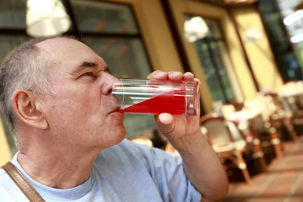 Starší člověk pije šťávu — Stock fotografie
