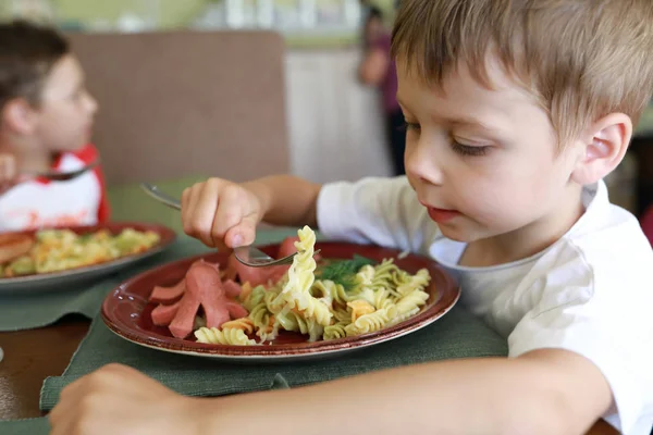 Criança comendo macarrão com salsichas — Fotografia de Stock