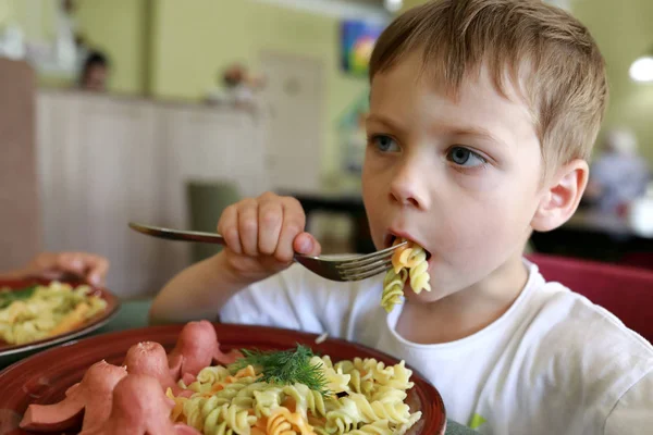 Ragazzo che mangia pasta con salsicce — Foto Stock