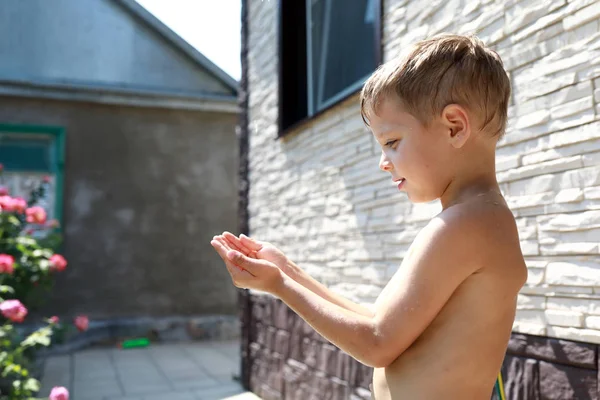 Niño captura gotas de agua con las manos —  Fotos de Stock