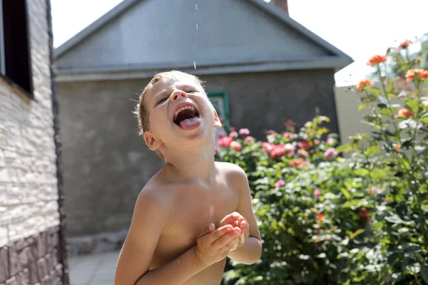 Ragazzo cattura gocce d'acqua con la bocca — Foto Stock