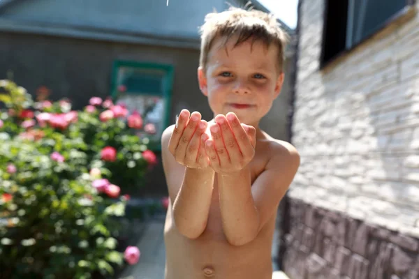 Child catches drops of water with hands — Stock Photo, Image