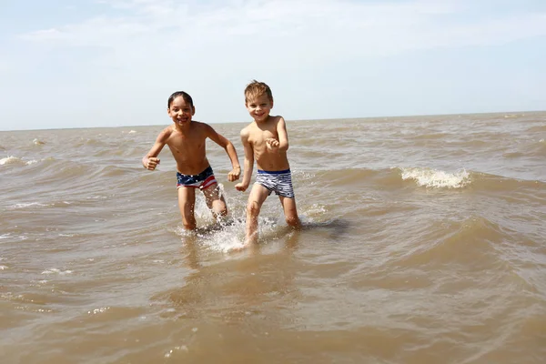 Мальчики бегут в море — стоковое фото