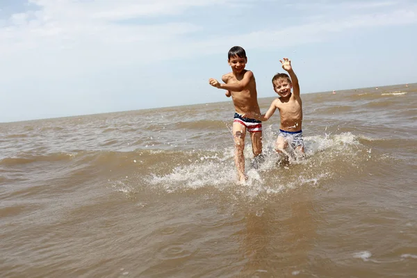 Hermanos corriendo en el mar — Foto de Stock