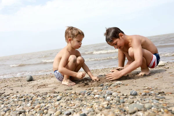 Crianças brincando com seixos na praia — Fotografia de Stock