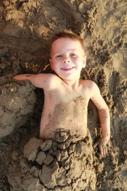 Mutlu çocuk sahilde kuma gömüldü