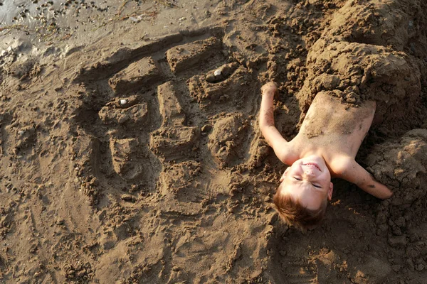 Menino enterrado na areia na praia — Fotografia de Stock