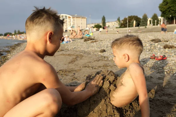 Kind vult zijn broer met zand — Stockfoto