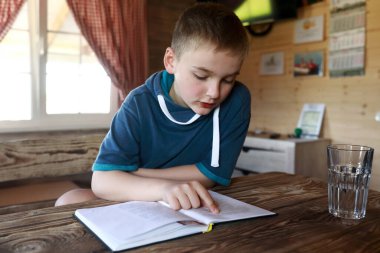 Evdeki masada çocuk kitabı okuyor.