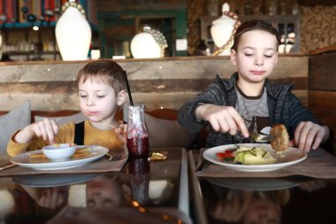İki kardeş lokantada yemek yiyor.