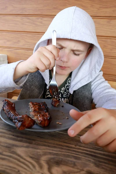 木のテラスで豚カルビを食べる子供 — ストック写真