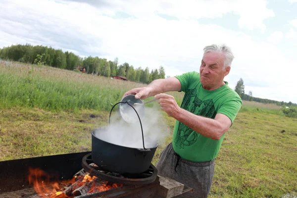 Senior Man Puts Vegetables Cauldron Cooking Russian Fish Soup Ukha — Stock Photo, Image