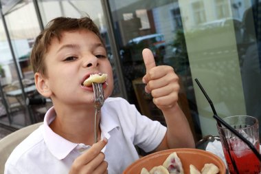 Restoranın terasında çocuk yiyen vareniki