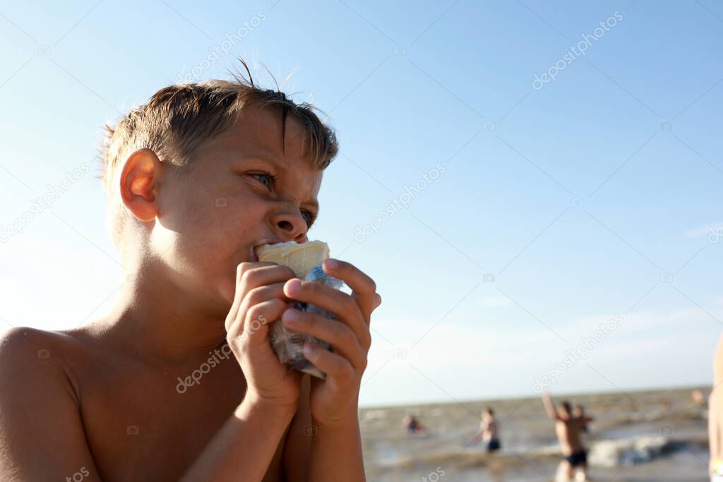 Boy eating ice cream on beach of Azov sea