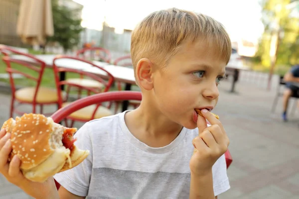 Child eating fries and burger in restaurant