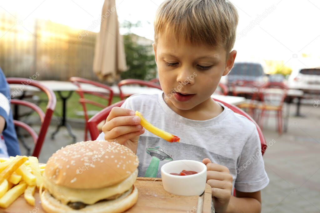 Child eating fries with ketchup in restaurant