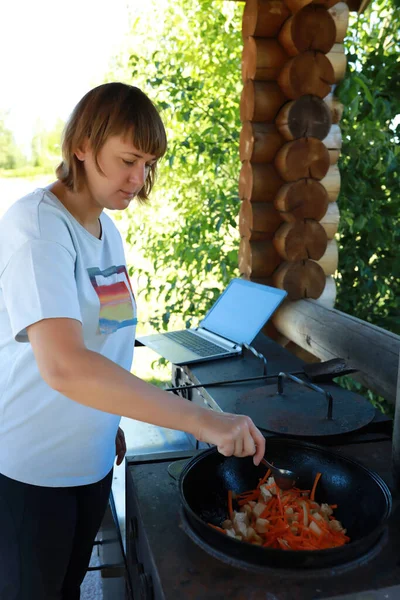 여자들은 필라프 만들기 위하여 고기와 양파와 당근을 넣는다 — 스톡 사진