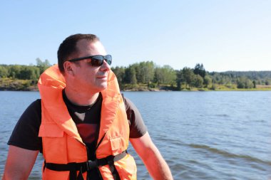 Portrait of man in life jacket on boat in Ladoga skerries clipart