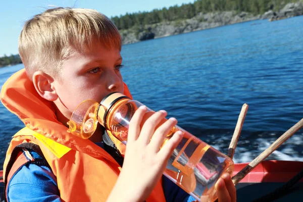 ラドーガのスケリーでボートの上のライフジャケットの子供飲料水 — ストック写真