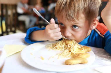 Çocuk restoranda nuggetlı spagetti yiyor.