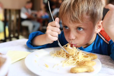 Restoranda nuggetlı spagetti yiyor.