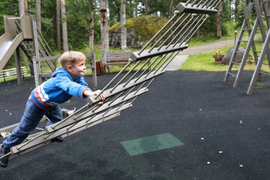 Çocuk dışarıda çocuk parkında merdivende sürünüyor.