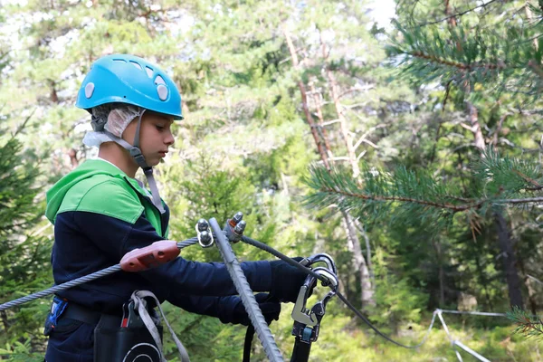 森の冒険公園で安全装置のキャビナーを使用することを学ぶ少年 — ストック写真