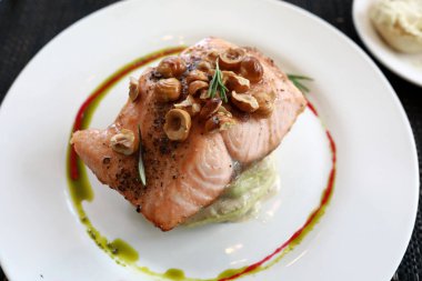 Lokantada beyaz tabakta fındıklı ve kabaklı alabalık.