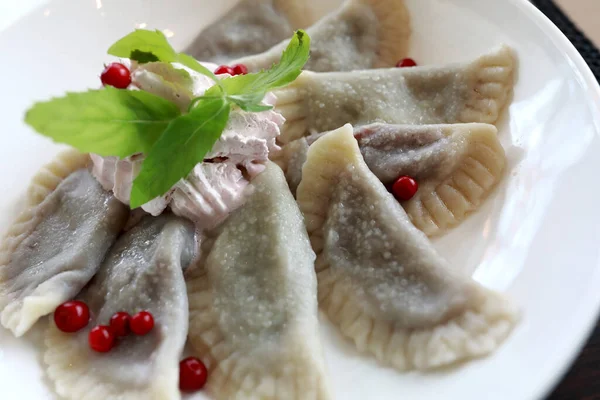 Sweet dumplings with cherries on white plate in a restaurant