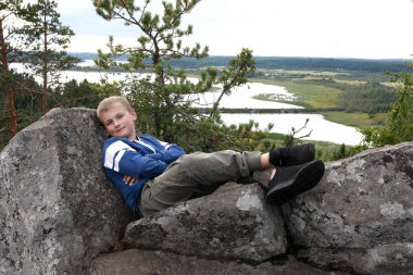 Çocuk yazın Paaso Dağı 'nın taşında oturuyor, Karelia.