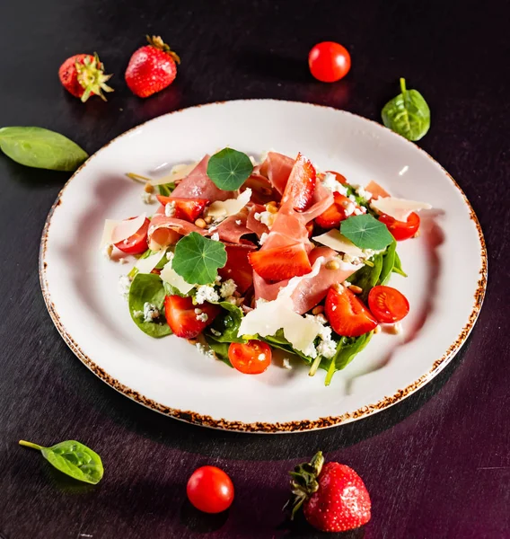 salad with cherry tomatoes, cheese, strawberries and nasturtium leaves