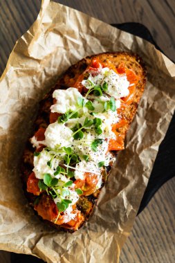 Kızarmış domatesli İtalyan bruschetta, mozzarella peyniri ve kesim tahtasında otlar.