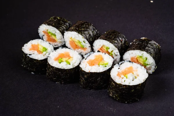 寿司卷放在深色背景的黑色石板上 — 图库照片