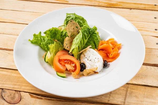 salad with mozzarella and salmon, wooden background