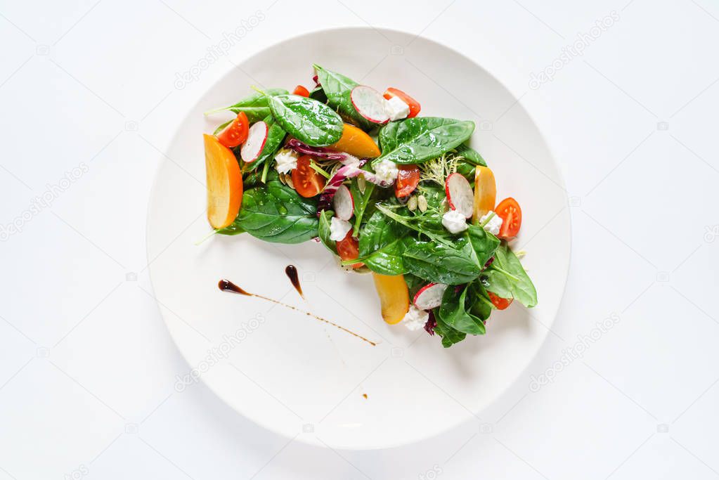 salad with spinach and persimmon on the white plate