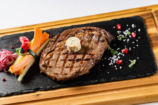 grilled Medium rare barbecue steak Ribeye with herb butter on cutting board