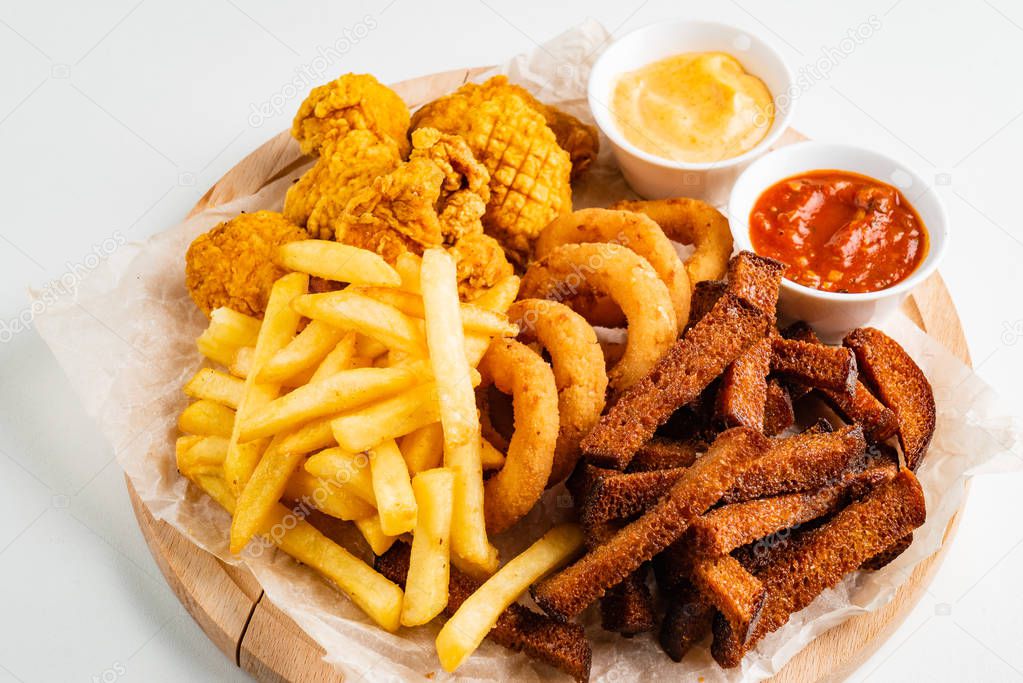 The beer plate with spicy chicken wings, calamari rings, fries onion rings, cheese balls, breaded, ketchup and mustard sauce