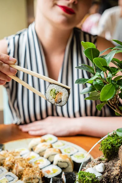 young woman eating sushi in the restaurant