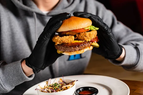 man in black gloves eating burger in the restaurant