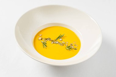 Beyaz arka planda balkabağı kremalı çorba.