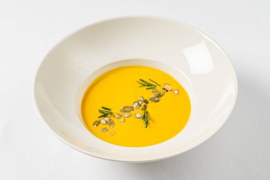 Beyaz arka planda balkabağı kremalı çorba.