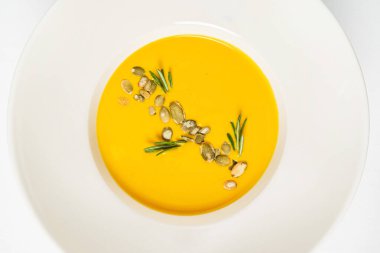 Beyaz arka planda balkabağı kremalı çorba.