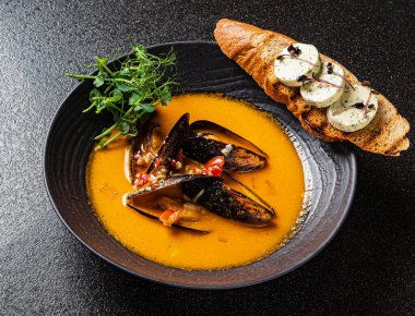 Siyah arka planda kızarmış ekmek ile deniz ürünleri çorbası.