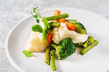 Beyaz tabakta haşlanmış sebze.