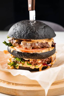 Ahşap arka planda iştah açıcı bir siyah hamburger.