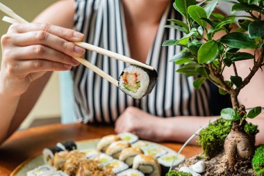 Restoranda suşi yiyen bir kadın.