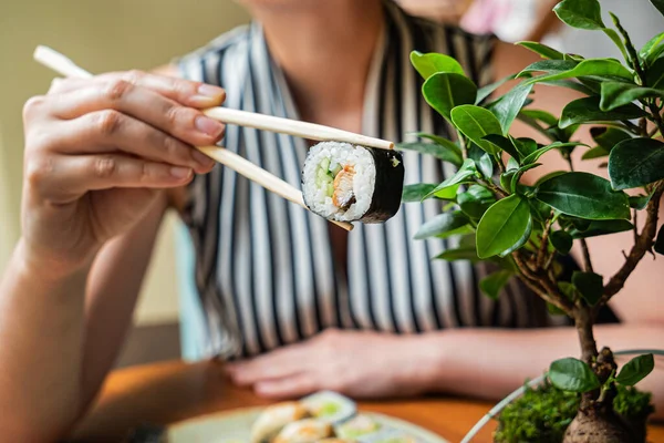 Restoranda suşi yiyen bir kadın.