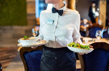 Garson, şenlikli bir etkinlikte et tabağı taşıyor.