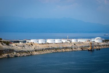 Arka planda dağ olan mavi deniz kıyısındaki fabrika 