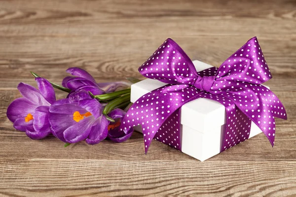 Confezione regalo bianca con fiocco viola e bouquet di crochi . — Foto Stock